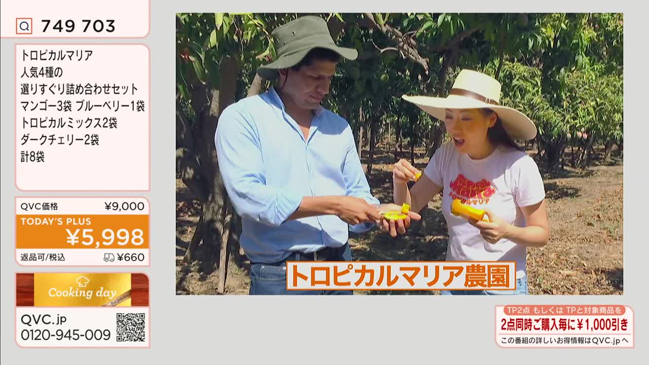 A man and a woman, both wearing hats, are in a field, holding and tasting pieces of yellow fruit. The scene is likely a segment on QVC in Japan, as indicated by the on-screen text.
