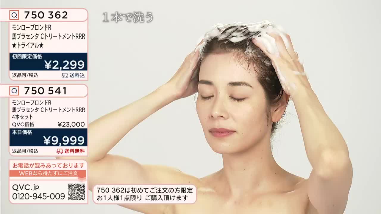 A woman with closed eyes massages shampoo into her hair. The QVC Japan screen displays product information, including the price of a hair treatment.
