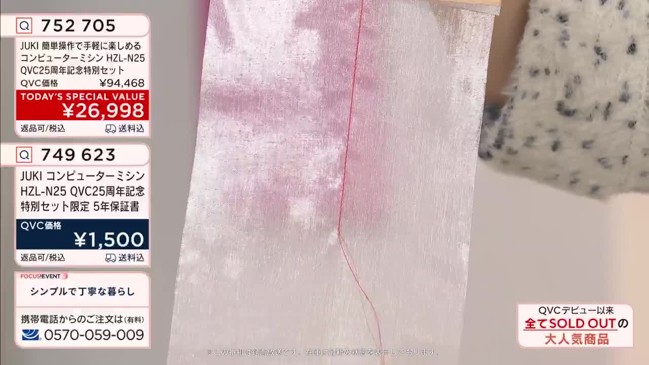 A thin red thread stitches a pale pink fabric. A fluffy white garment with dark speckles hangs to the right.