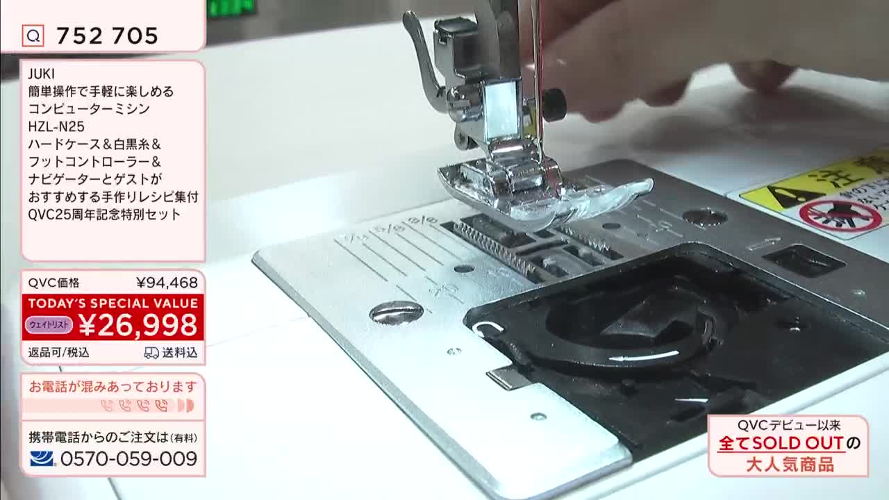 A hand guides fabric under the needle of a JUKI sewing machine. The machine's presser foot is lowered, ready to stitch.