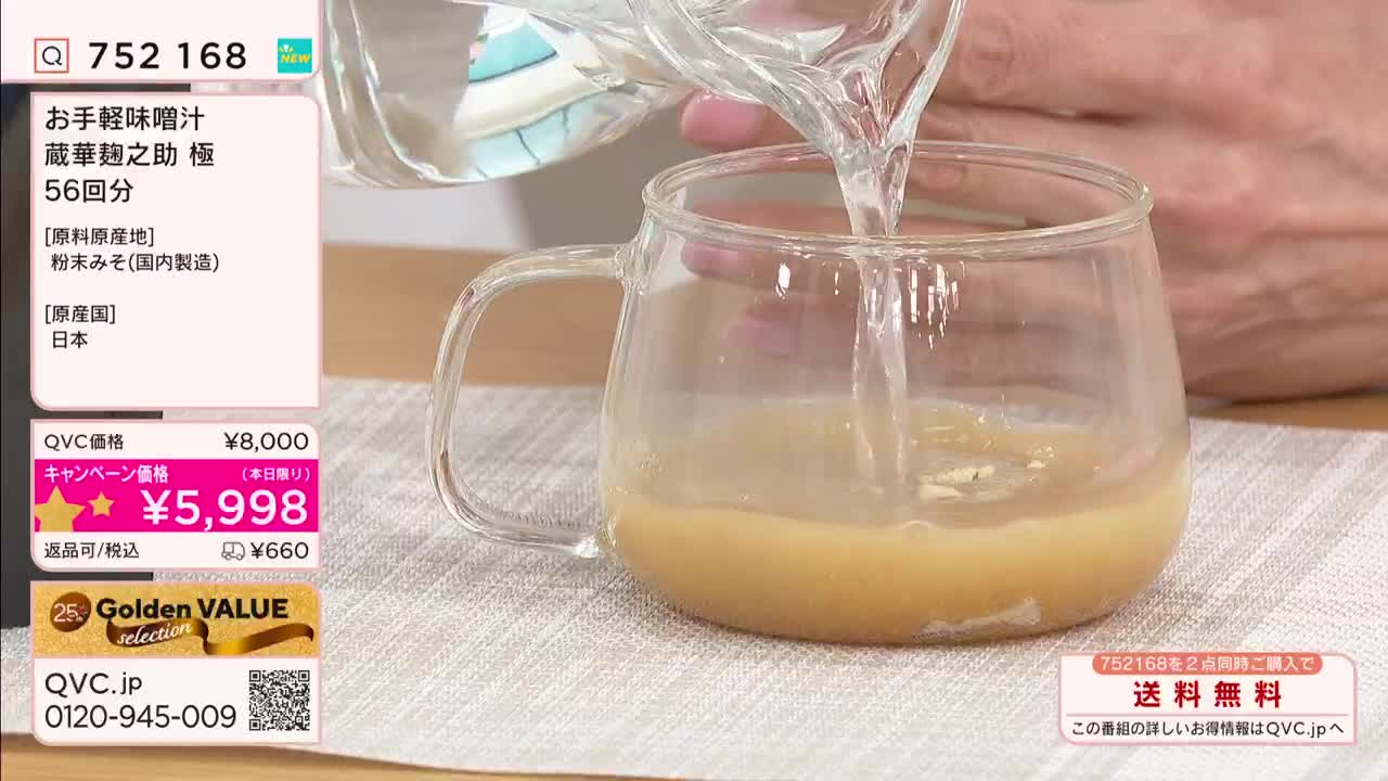 Clear water streams into a glass mug, mixing with a light brown liquid. This is happening on a QVC broadcast, likely in Japan, as a product is being prepared for demonstration. Clear water streams into a glass mug, mixing with a light brown liquid. This is happening on a QVC broadcast, likely in Japan, as a product is being prepared for demonstration.