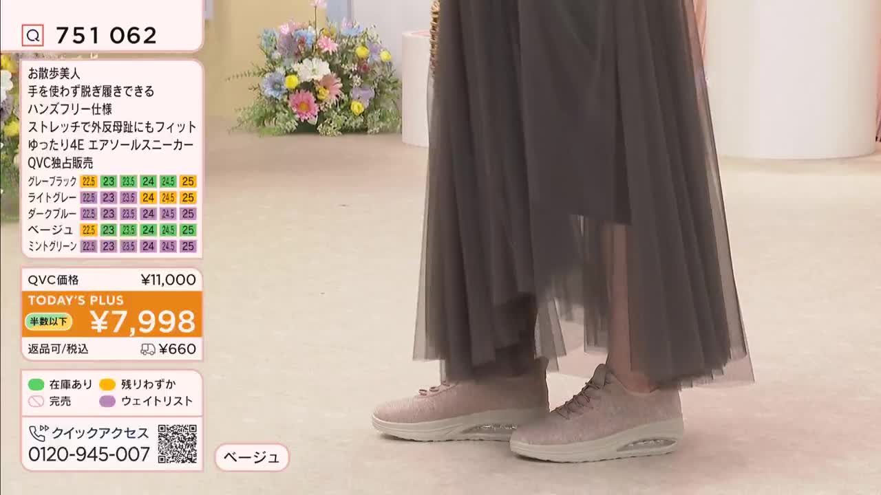 A woman stands in light pink sneakers, her long, sheer grey skirt flowing around her ankles. On a screen beside her, the QVC price for these shoes is displayed.