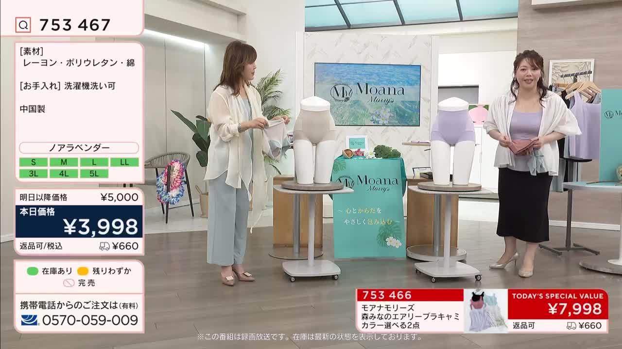 A woman in a light blue jumpsuit holds up a garment for display. Another woman stands nearby, holding a pink wallet.