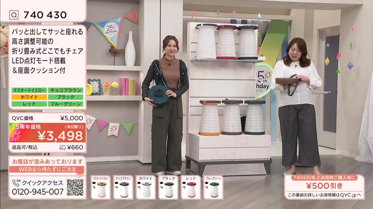 A woman in a dark jacket and olive pants holds a teal collapsible stool. Another woman in a white blouse and gray pants gestures toward a display of similar stools. A woman in a dark jacket and olive pants holds a teal collapsible stool. Another woman in a white blouse and gray pants gestures toward a display of similar stools.