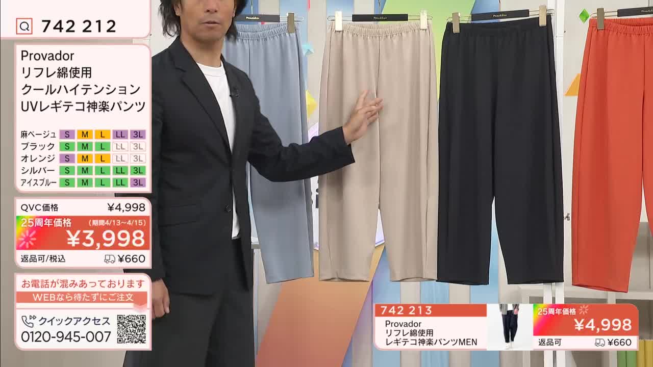 A man in a suit gestures towards a row of pants hanging on display. The pants, in light blue, beige, black, and orange, are presented as part of a QVC broadcast.