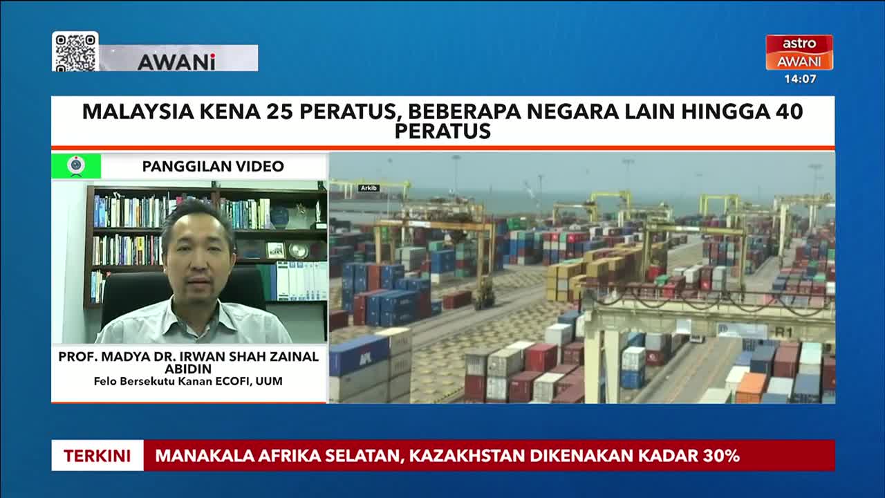 A man is speaking on Astro Awani, with a news banner at the top indicating the topic. Behind him, a busy port scene shows stacks of colorful shipping containers.
