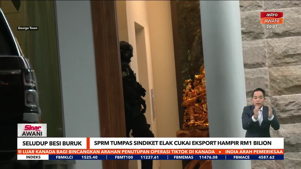 A figure in dark clothing stands in a doorway, framed by a news report from Astro Awani. The anchor gestures while reporting on a story about a raid in George Town.
