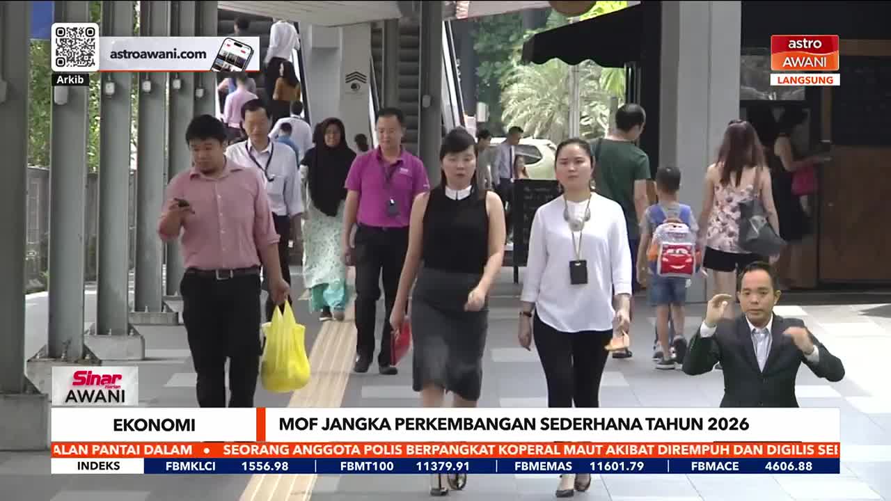 People are walking along a walkway, some looking at their phones, others carrying bags.  Astro Awani's news broadcast is underway, with a presenter gesturing in the foreground.
