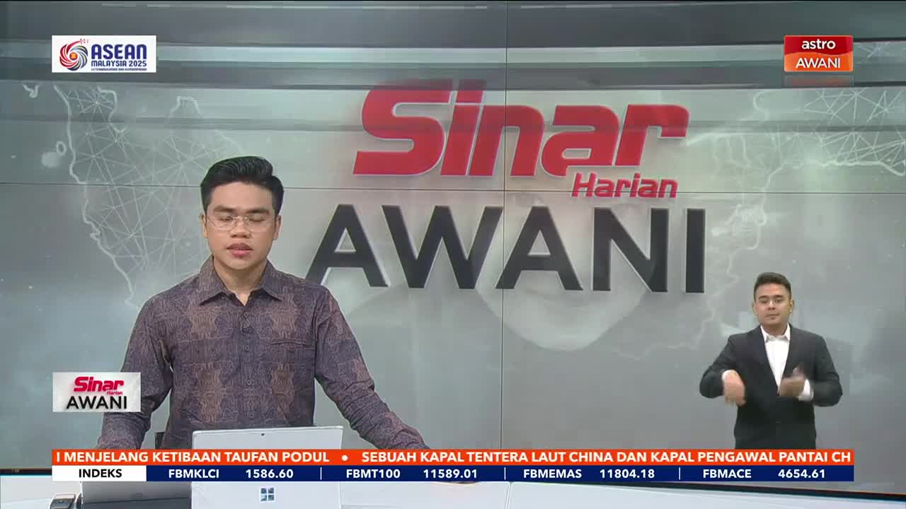 A man in glasses and a patterned shirt speaks from behind a desk, the "Sinar Harian AWANI" logo prominent behind him. To his right, another man in a suit uses sign language.
