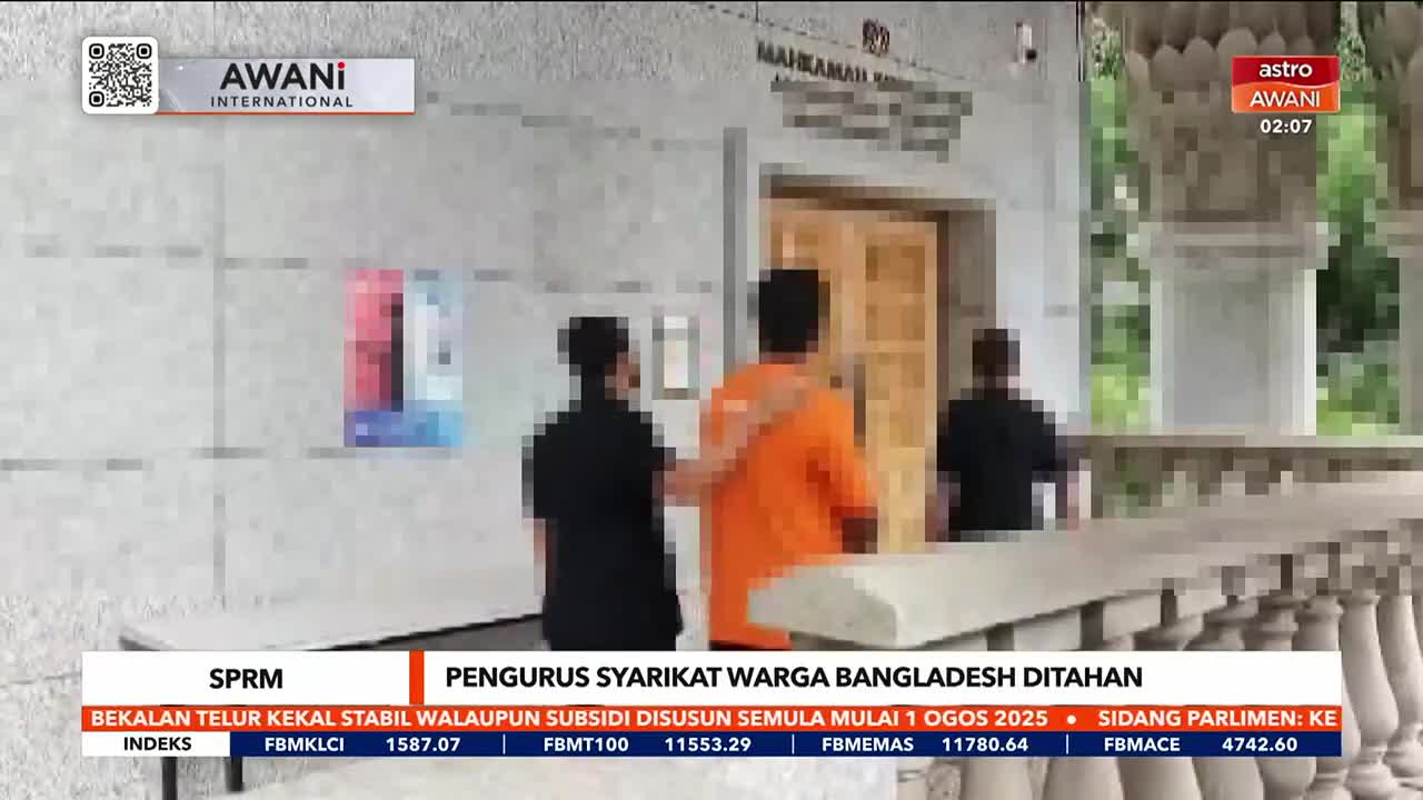 Three men are walking towards a building entrance, one in an orange shirt, flanked by two others in black. The Astro Awani news ticker at the bottom of the screen reports a detention in Malaysia.
