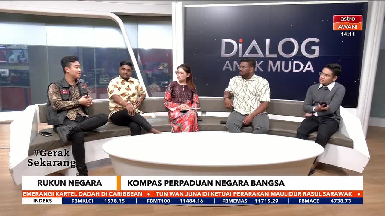 A panel of five people sits on a curved sofa, part of a set for Astro Awani's "Dialog Anak Muda." The man on the left gestures with his hands as he speaks.
