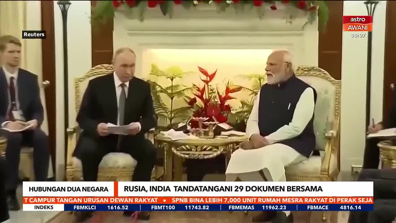 On Astro Awani, the Russian and Indian leaders sit facing each other, both holding papers. A caption at the bottom of the screen announces the signing of 29 documents between the two countries.
