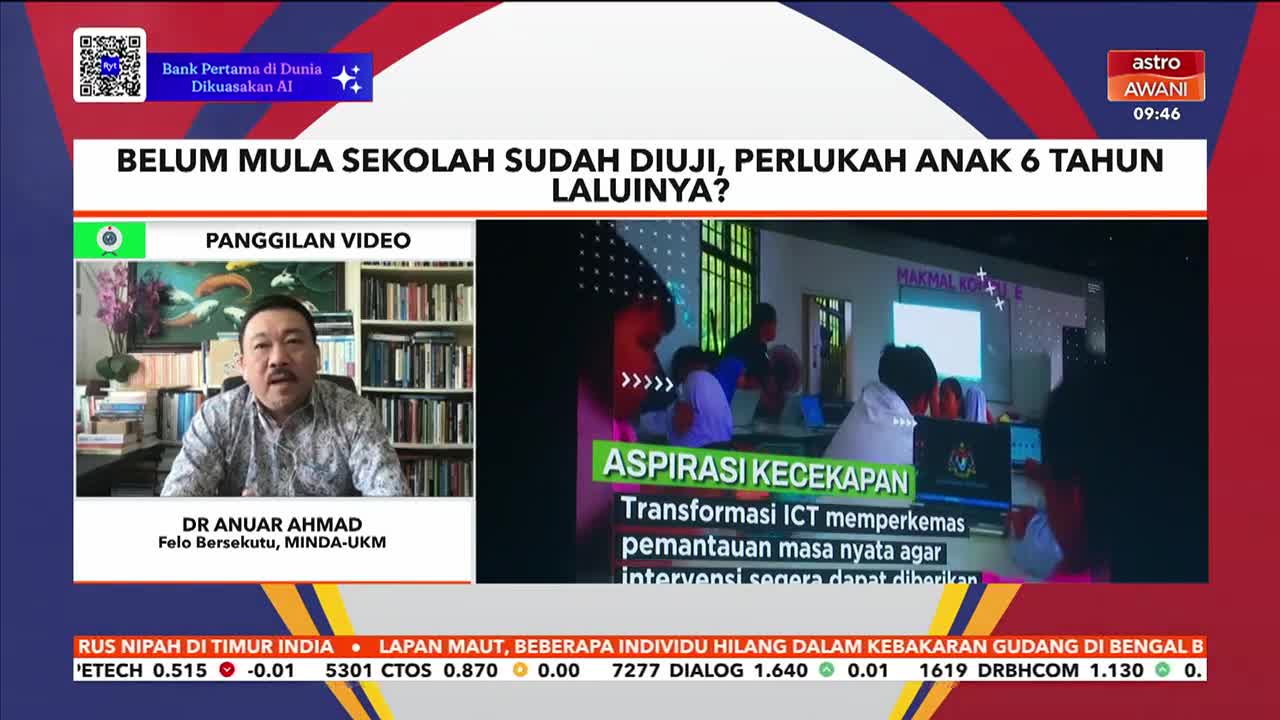 A man in a patterned shirt speaks from a bookshelf-lined room, while a video feed shows students gathered around computers. The Astro Awani chyron at the top asks if six-year-olds need to be tested before starting school. A man in a patterned shirt speaks from a bookshelf-lined room, while a video feed shows students gathered around computers. The Astro Awani chyron at the top asks if six-year-olds need to be tested before starting school.