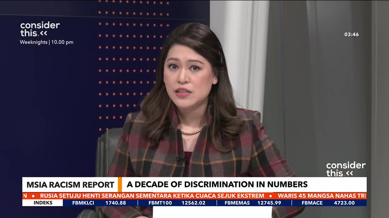 A woman in a plaid jacket speaks directly to the camera, her words overlaid with a chyron about a Malaysian racism report. The Astro Awani logo is visible in the corner. A woman in a plaid jacket speaks directly to the camera, her words overlaid with a chyron about a Malaysian racism report. The Astro Awani logo is visible in the corner.