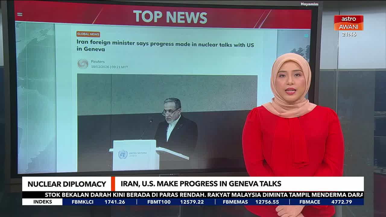 A woman in a red top and hijab stands to the right, speaking. To her left, a large screen displays "TOP NEWS" and a headline about nuclear talks. A woman in a red top and hijab stands to the right, speaking. To her left, a large screen displays "TOP NEWS" and a headline about nuclear talks.