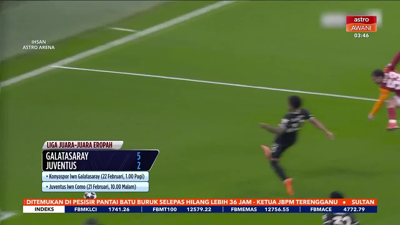 A player in a black and white kit kicks the ball forward on the green pitch. Another player in a red and yellow kit runs towards him. A player in a black and white kit kicks the ball forward on the green pitch. Another player in a red and yellow kit runs towards him.