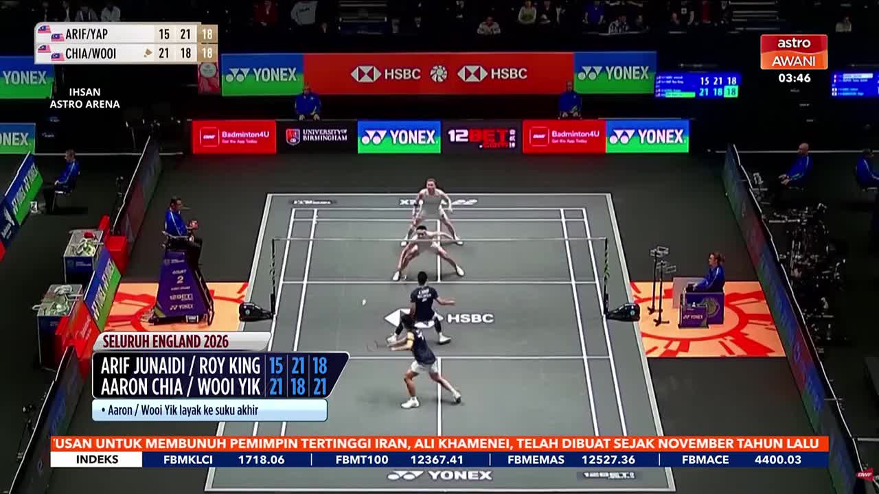 Two badminton players in dark shirts lunge for a shot as their opponents in white stand ready. The scoreboard shows Malaysia's Aaron Chia and Wooi Yik have won the match.