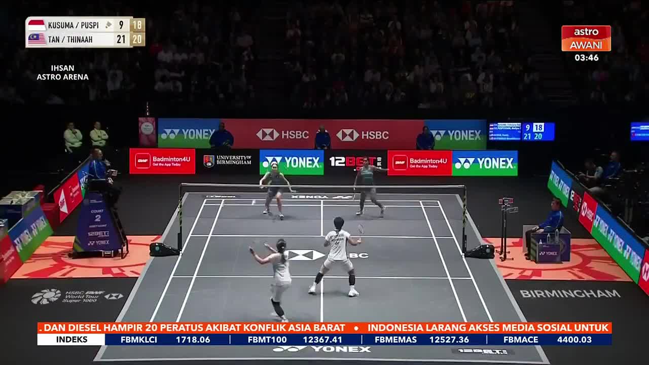 The players are in the middle of a rally, one player lunging forward to return a shot.  Astro Awani is broadcasting this badminton match live.