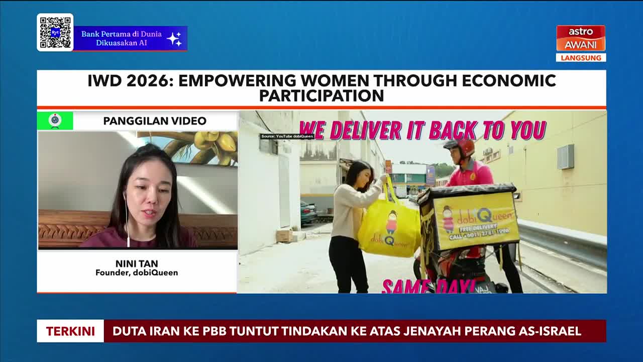 A woman in a maroon top is on a video call, speaking into a microphone. Beside her, a delivery rider on a motorcycle hands a large yellow bag to another woman. The Astro Awani logo is visible in the corner.