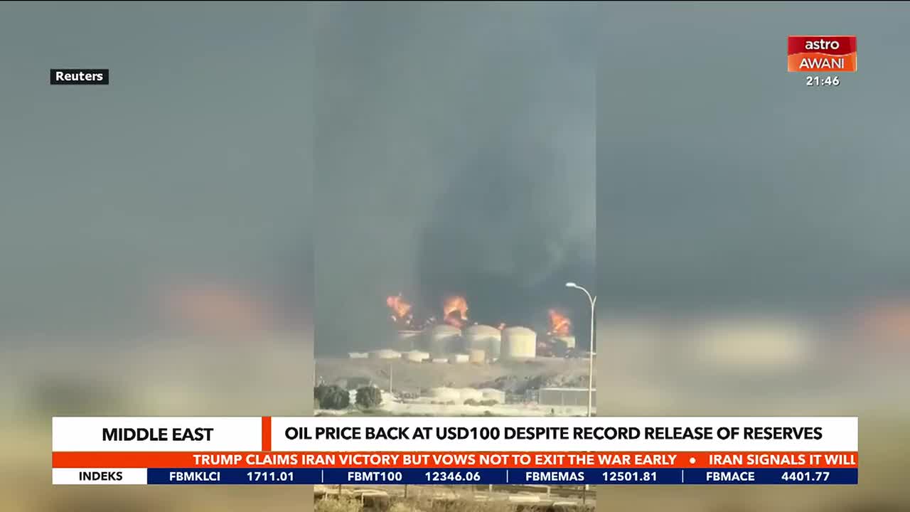 Flames erupt from several large storage tanks, sending thick smoke billowing into the sky. The scene unfolds against a hazy, overcast backdrop, with a news ticker from Astro Awani at the bottom of the screen.