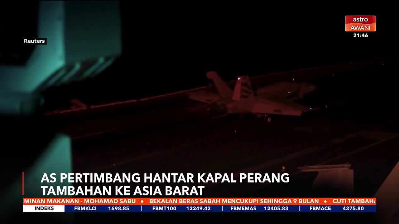 A fighter jet is about to land on an aircraft carrier at night. The red lights of the carrier deck illuminate the scene.