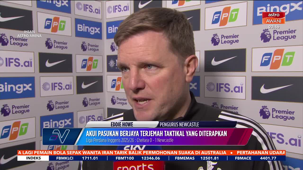 Eddie Howe speaks into a microphone, his face illuminated by the bright lights of the press room. Behind him, a wall of logos from the Premier League and its sponsors, including FPT and Bingx, are clearly visible.