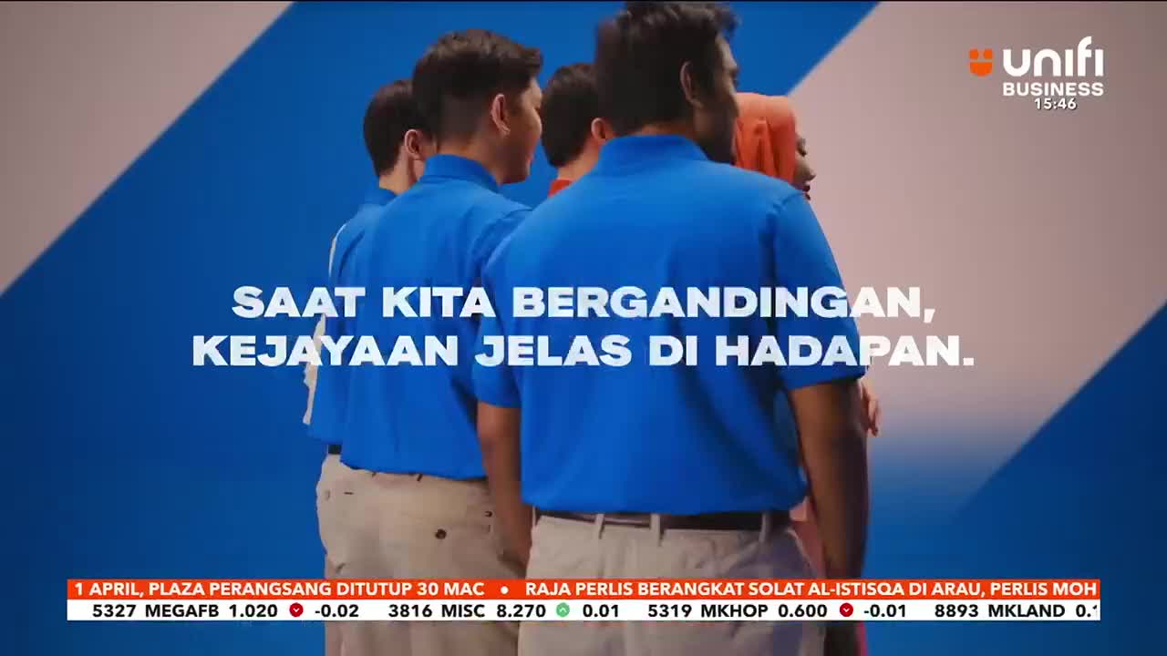 A group of people in blue shirts stand together, their backs to me. On the screen, the words "SAAT KITA BERGANDINGAN, KEJAYAAN JELAS DI HADAPAN" are displayed.