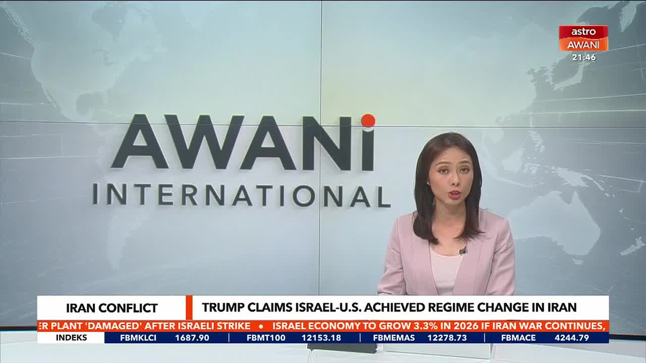 A news anchor speaks directly to the camera, her voice clear and steady. Behind her, the "AWANI INTERNATIONAL" logo fills a large screen.