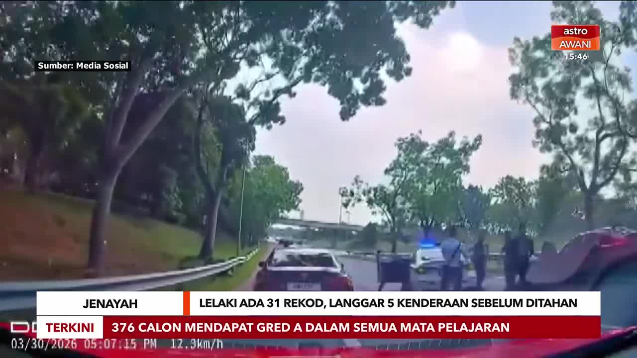 A police car with flashing blue lights is parked on the side of the road, with officers standing around it. A dark sedan is stopped ahead of it, and another vehicle, possibly red, is partially visible in the foreground.