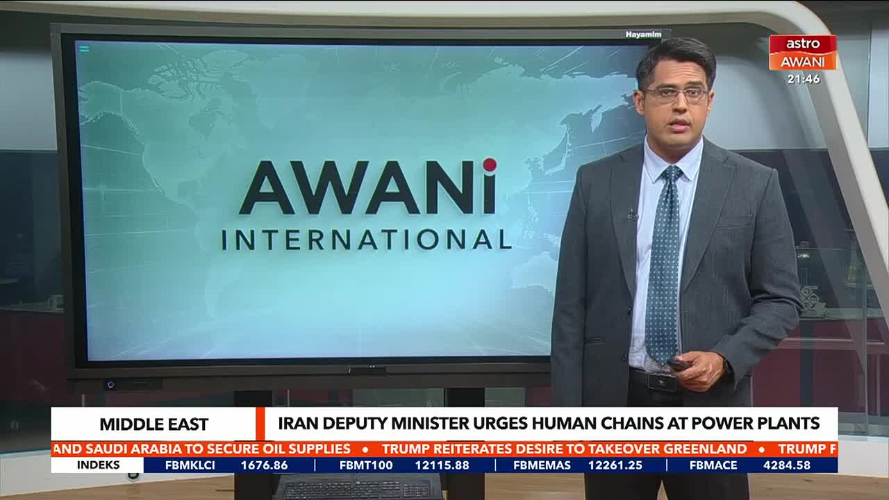 A news anchor stands before a large screen displaying the "AWANI INTERNATIONAL" logo. Below, a ticker scrolls with headlines, including one about the Middle East and Saudi Arabia securing oil supplies.