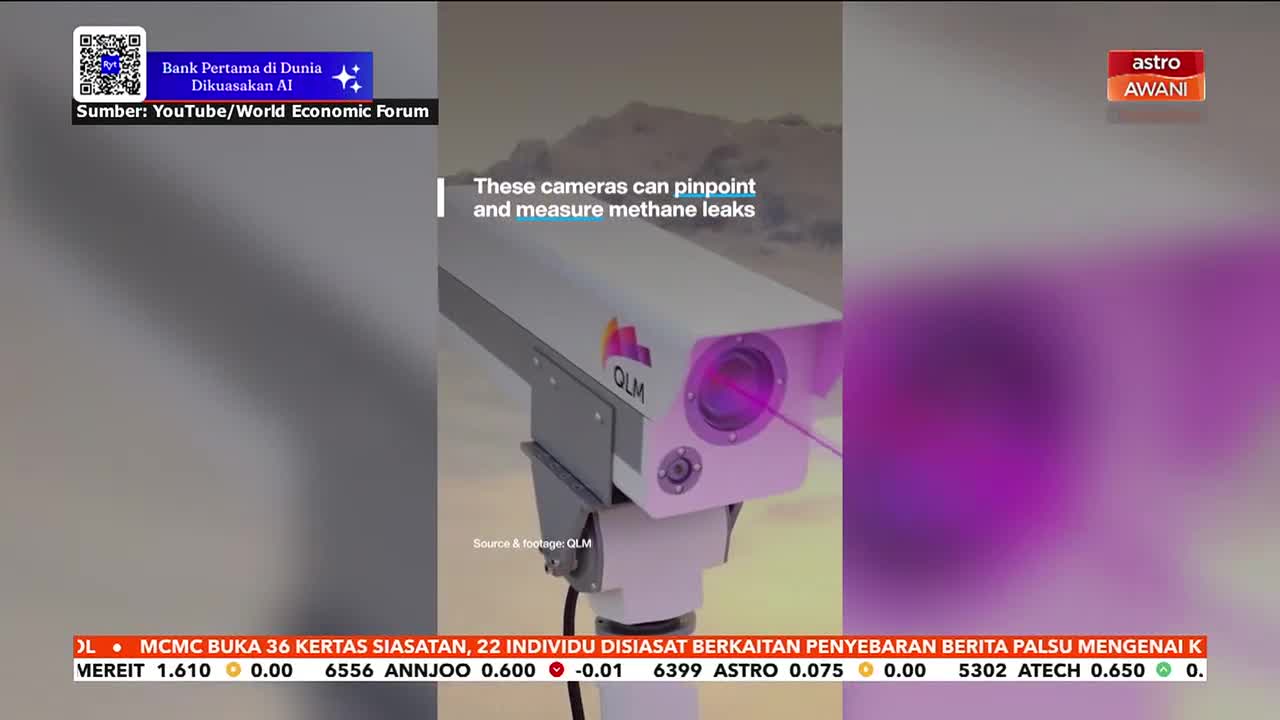 A white camera with the QLM logo is mounted on a pole, its lens emitting a purple beam. Astro Awani's logo appears in the upper right corner, and a ticker at the bottom displays stock information.