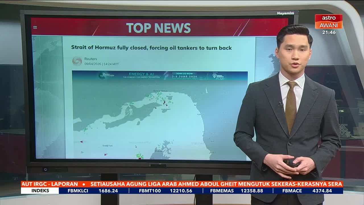 A man in a suit stands before a large screen displaying "TOP NEWS" and a map with the headline "Strait of Hormuz fully closed, forcing oil tankers to turn back." Below the screen, scrolling text in Malay provides financial updates.