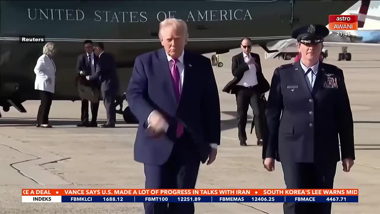 Donald Trump walks across the tarmac, a bright pink tie visible against his dark suit. A woman in a crisp military uniform marches alongside him, her gaze forward.
