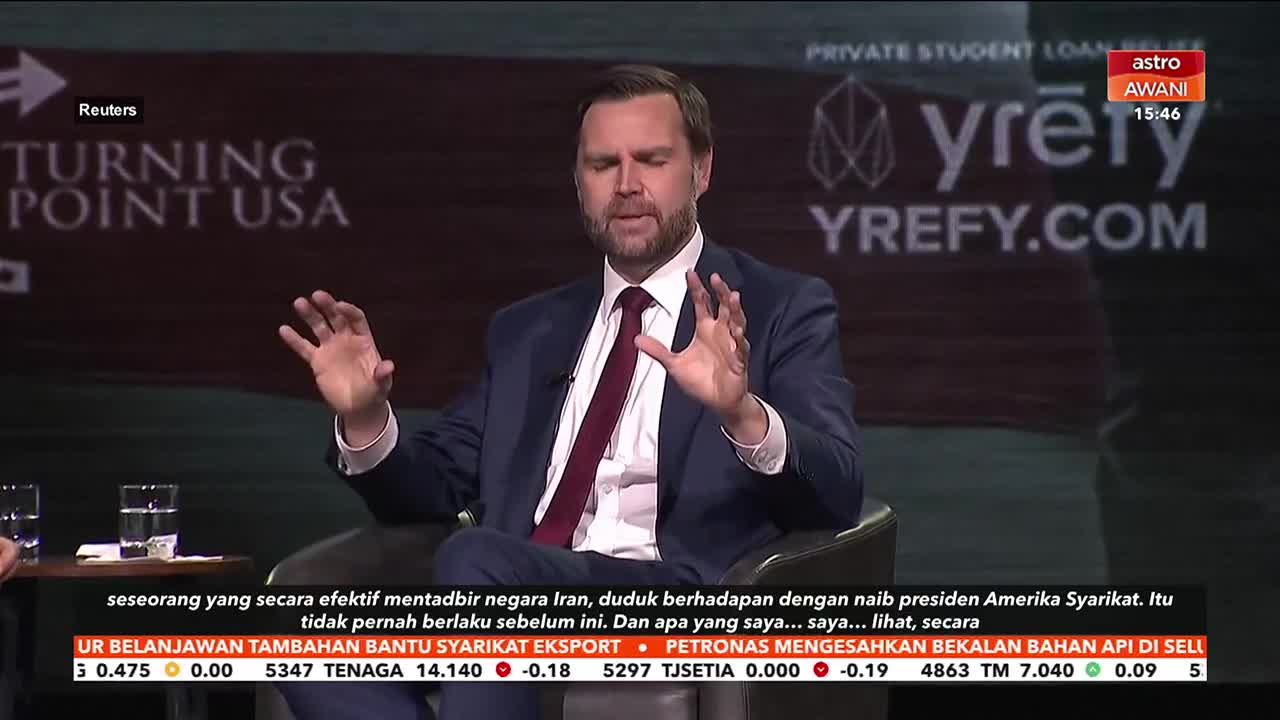 A man in a suit gestures with both hands while speaking on a panel. The Astro Awani chyron at the top right indicates this is a broadcast from Malaysia.
