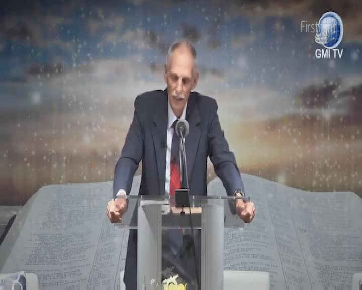 A man in a dark suit stands at a clear podium, speaking into a microphone. Behind him, a backdrop depicts a starry sky and a giant open book, with the Firstlight GMI TV logo in the corner.
