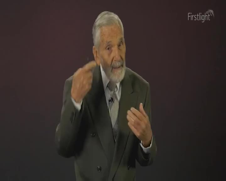 The man in the suit gestures towards his head, then opens his hands as if explaining something. The Firstlight logo is visible in the corner.
