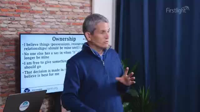 A man in a blue quarter-zip sweater gestures with his hands while speaking. Behind him, a screen displays bullet points under the heading "Ownership."