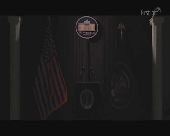 The American flag hangs still beside a podium. A seal of the President of the United States is visible on the wall behind it. The American flag hangs still beside a podium. A seal of the President of the United States is visible on the wall behind it.