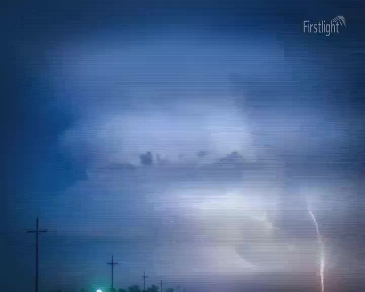 A jagged bolt of lightning splits the dark, stormy sky. The storm rolls in over the New Zealand landscape, silhouetting power poles against the dramatic light. A jagged bolt of lightning splits the dark, stormy sky. The storm rolls in over the New Zealand landscape, silhouetting power poles against the dramatic light.