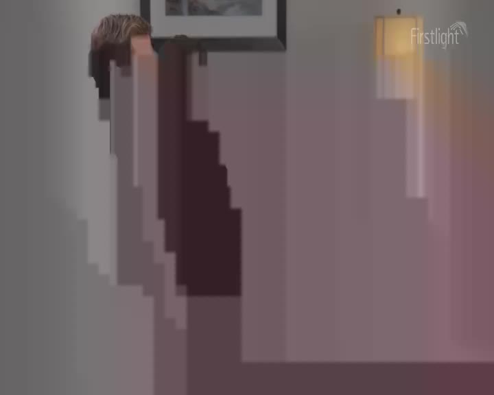 A person's head and shoulders are visible, their hair a light brown. A lamp casts a warm glow on the wall beside them.