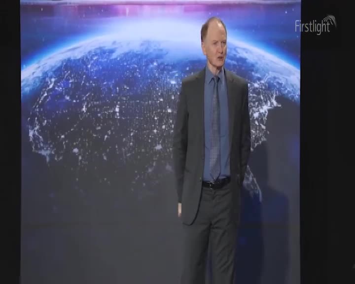 A man in a dark suit stands before a massive screen displaying a nighttime view of Earth, its cities glowing like scattered embers. The Firstlight logo sits in the corner, a subtle reminder of the broadcast.