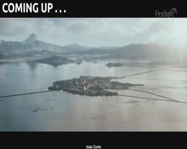 A small, clustered settlement sits on an island, connected by causeways across a vast, misty lake. Jagged, snow-capped mountains rise in the distance, their peaks shrouded in the soft light of early morning.