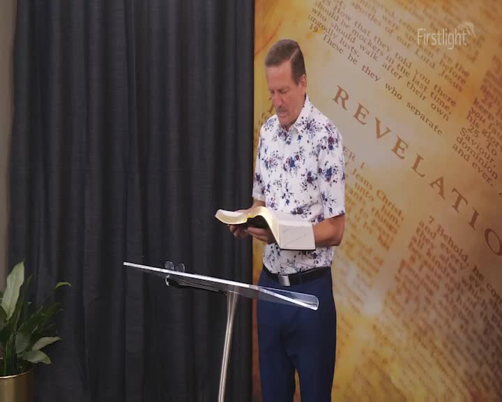 A man stands at a lectern, reading from an open Bible. Behind him, a backdrop displays text from the Book of Revelation. A man stands at a lectern, reading from an open Bible. Behind him, a backdrop displays text from the Book of Revelation.