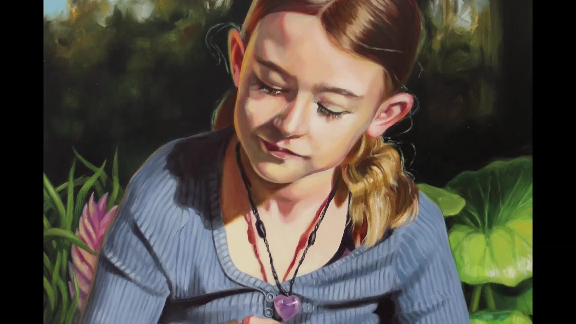 A young girl with light brown hair is gazing downward, her eyes closed and a gentle smile playing on her lips. She wears a blue cardigan and a heart-shaped pendant hangs around her neck.
