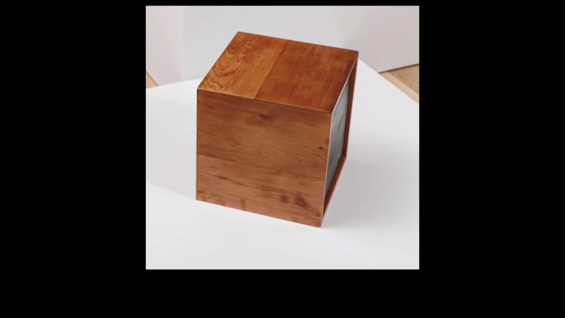 A polished wooden box sits on a white surface. The grain of the wood is clearly visible on its top and sides.
