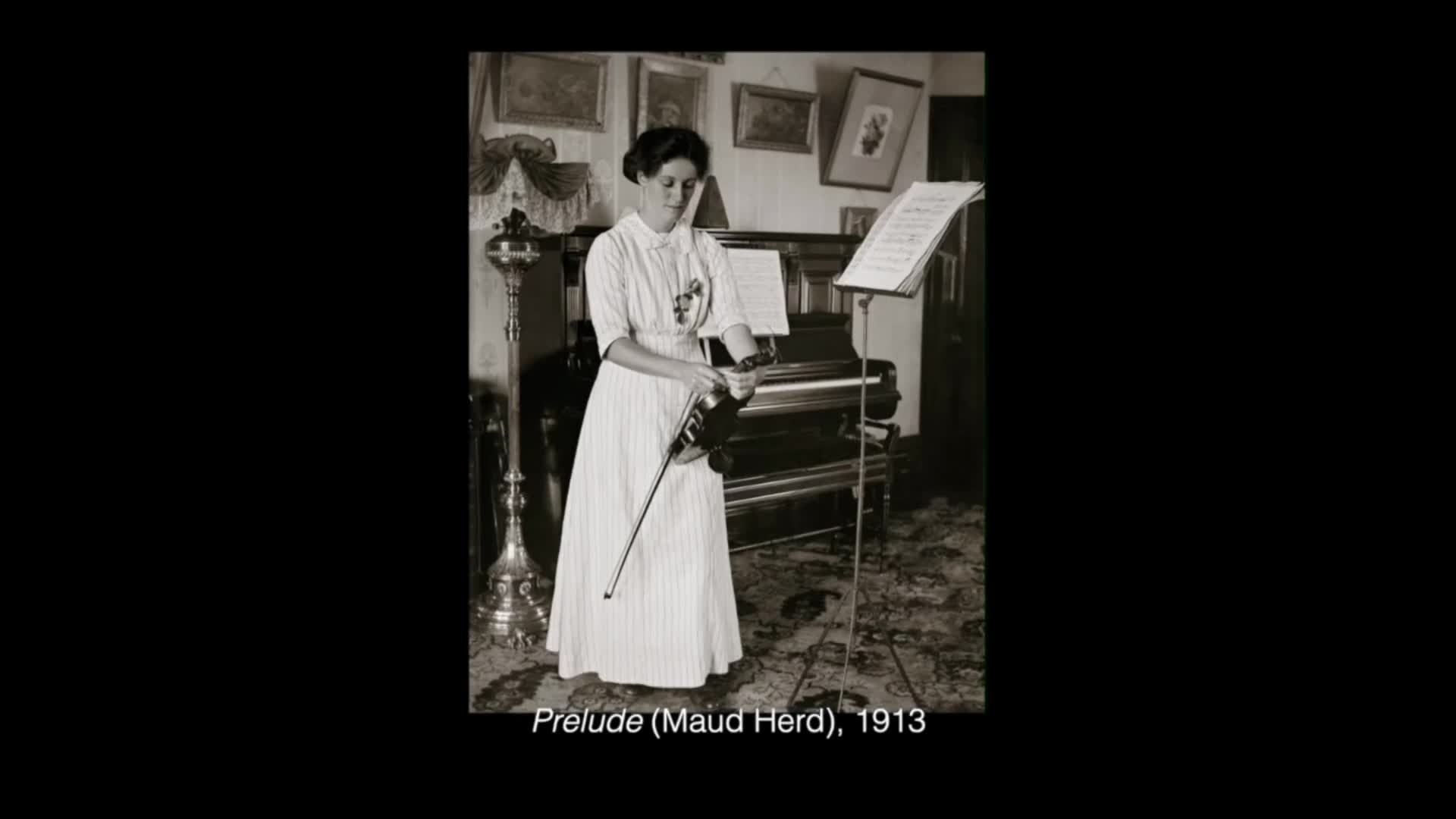 A woman in a long striped dress stands by a piano, holding a violin and bow. She looks down at the instrument, her fingers poised to play. A woman in a long striped dress stands by a piano, holding a violin and bow. She looks down at the instrument, her fingers poised to play.