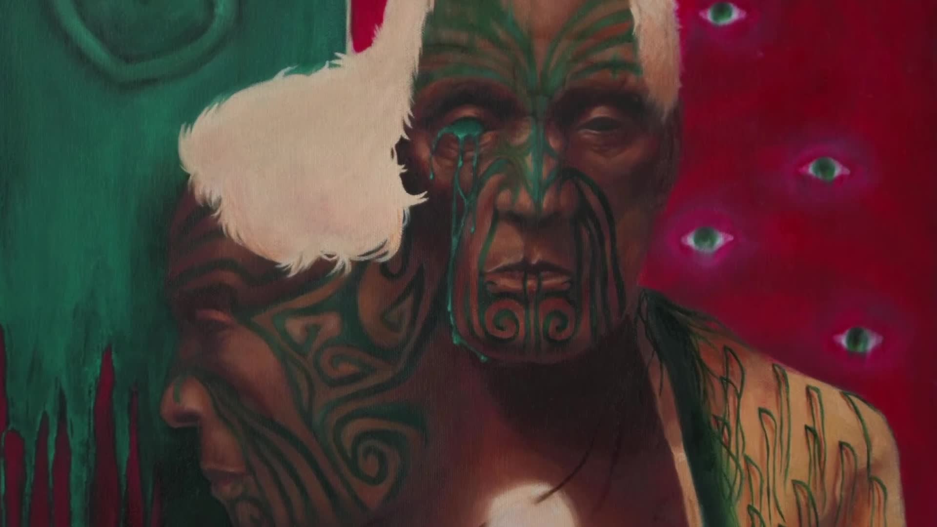 A man with a moko on his face and shoulders stands against a vibrant red background dotted with glowing eyes. Green markings drip down his face, resembling tears.