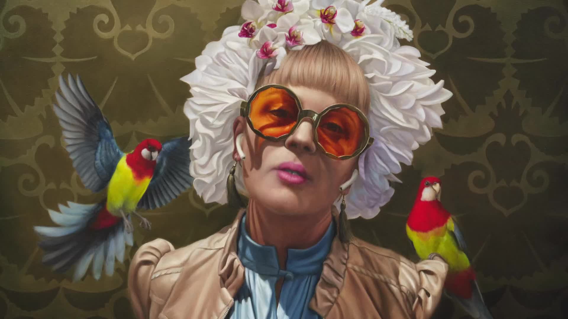 A woman with an elaborate white headdress and orange-tinted sunglasses turns her head slightly. Two small, vibrantly colored parrots flank her, one perched on her shoulder and the other in flight.