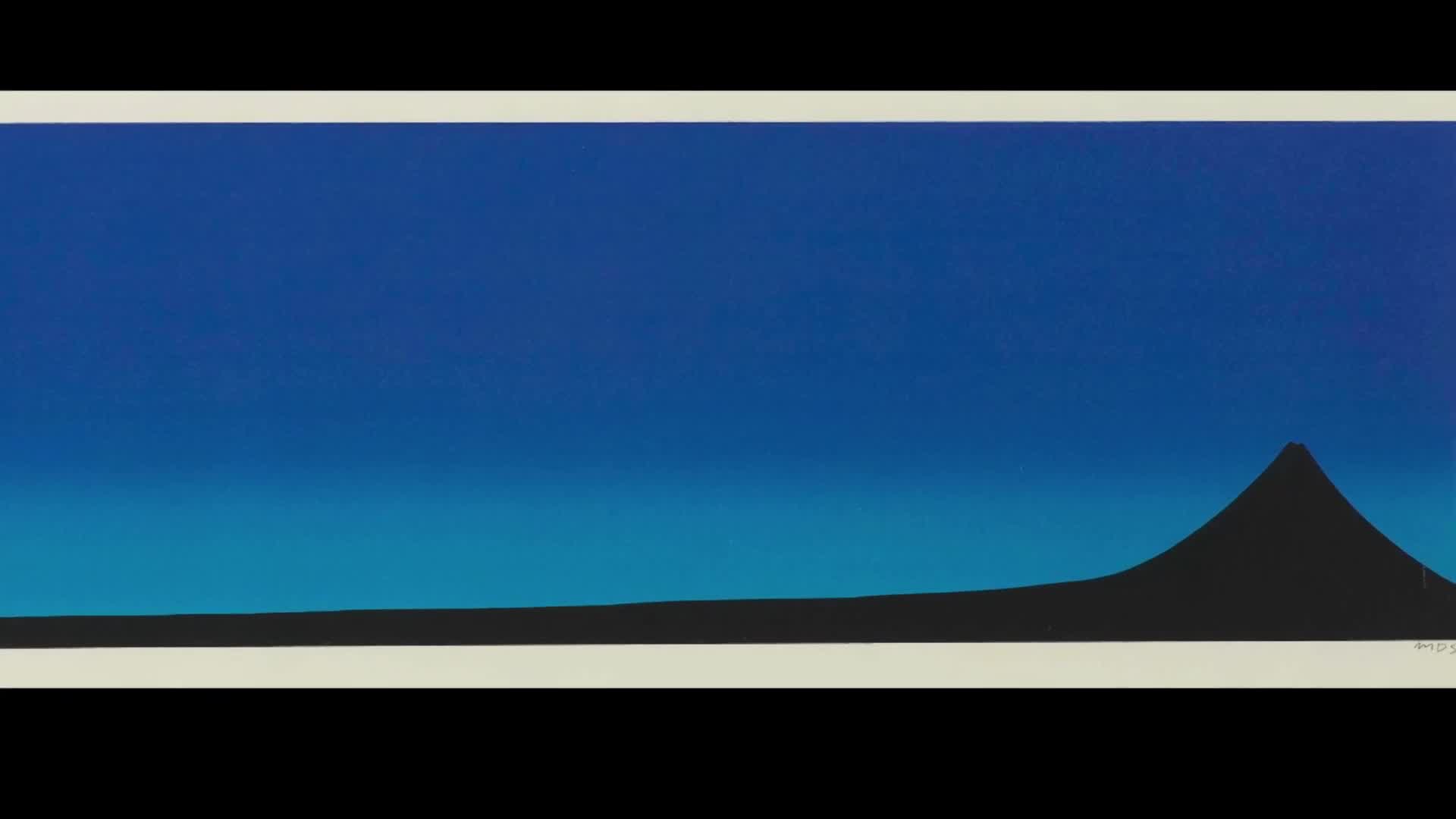 The sky above the horizon is a deep, clear blue, fading to a lighter shade near the land. A dark, conical mountain rises sharply from the flat, black ground.