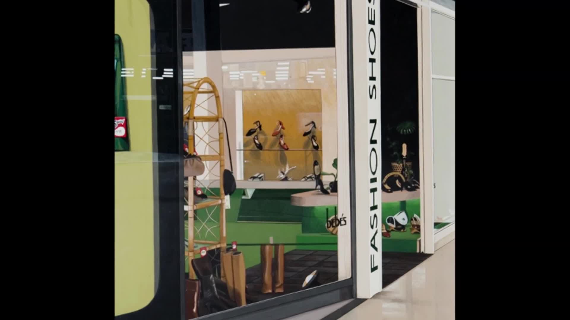 A shoe store window displays a collection of footwear, including several pairs of women's heels on shelves. A tall, woven rack with handbags hangs to the left of the display.